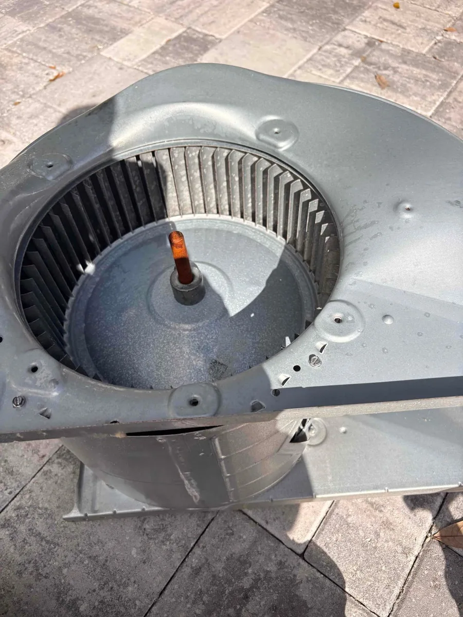 Blower assembly pulled out of an air handler on a Liberty Air and Electric job and set on pavers, with the blower wheel inside its housing.