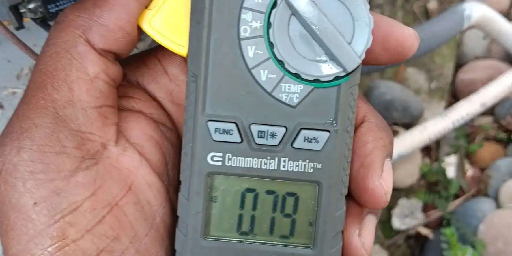 Liberty Air and Electric technician holding a clamp meter reading amp draw at an AC condenser in Kissimmee, Florida.