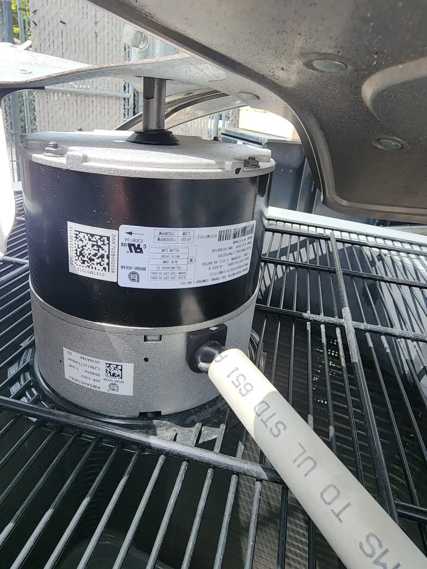 Replacement condenser fan motor staged on top of a residential AC unit during a Liberty Air and Electric service call in Boca Raton, Florida.