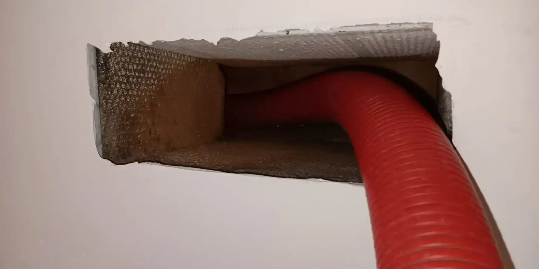 Vacuum hose run into an open supply duct boot during a residential duct cleaning.