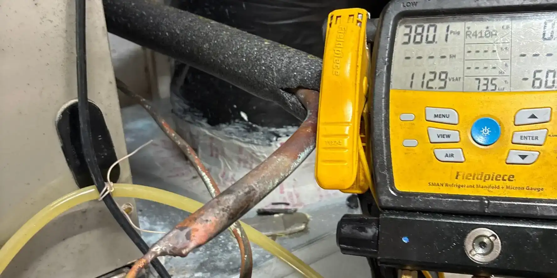 Fieldpiece manifold and micron gauge clamped on a copper line set during a Liberty Air and Electric isolation test.