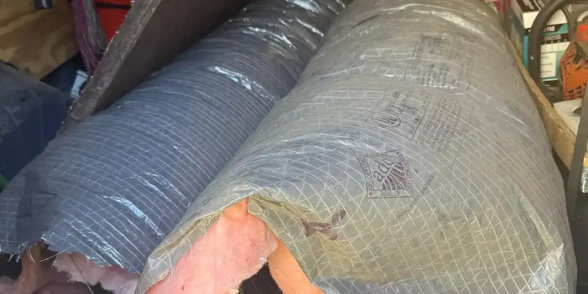 Sections of insulated flex duct with the outer jacket and fiberglass batt cut open, showing the thin inner liner and its wire helix.
