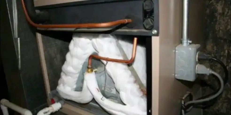 An evaporator coil buried in a solid block of ice inside an open air handler cabinet.
