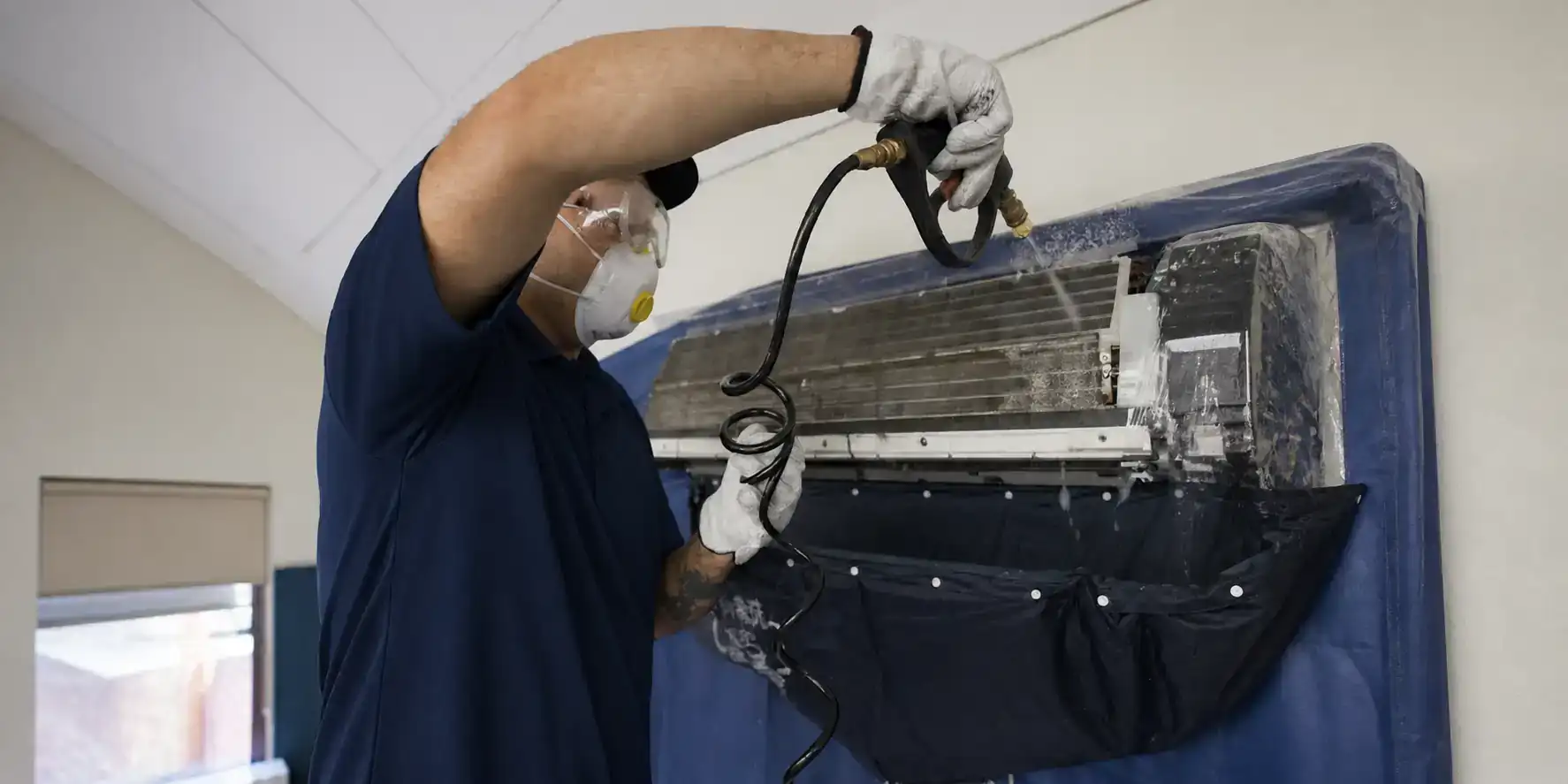 AC tech cleaning a mini-split indoor coil for IAQ.