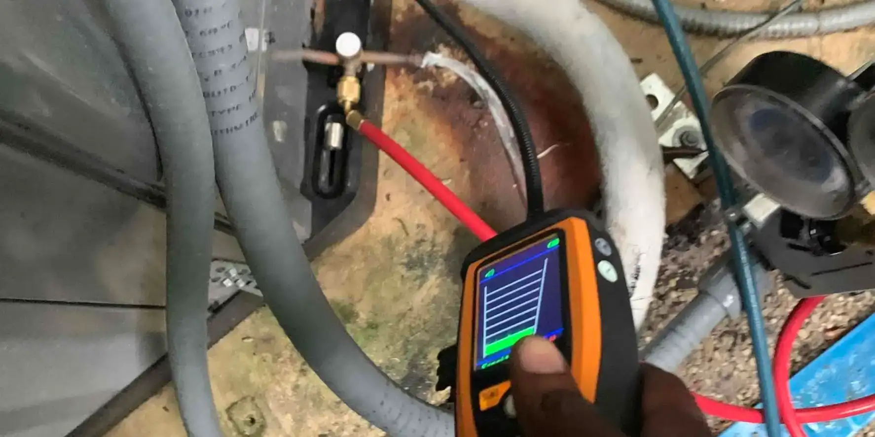 Liberty Air and Electric tech checking AC service valves with an infrared refrigerant leak detector.