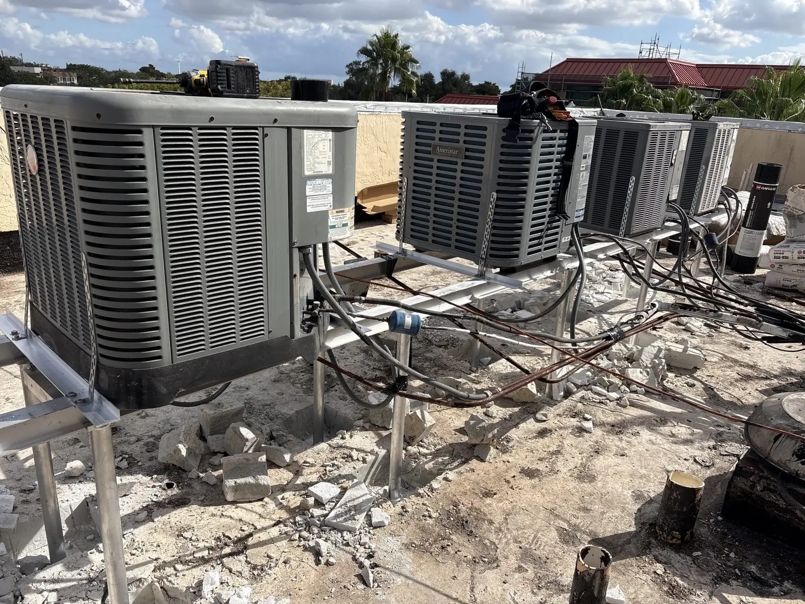Liberty Air and Electric reinstalled condensers on new aluminum HVHZ-rated stands during an active re-roof project, with the existing roof opened up around the work area.