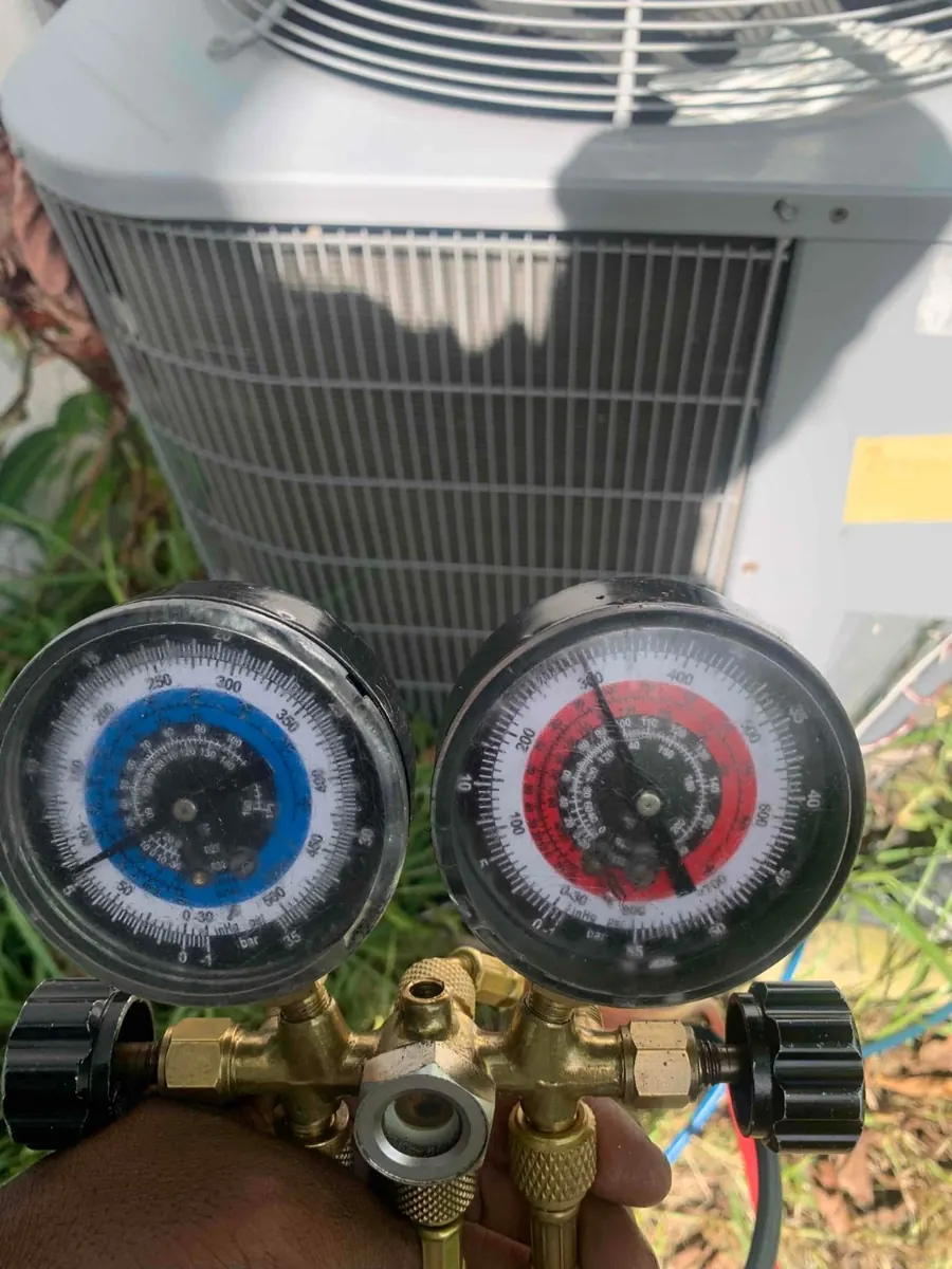 Liberty Air and Electric tech holding manifold gauges in front of an outdoor AC unit to check the refrigerant charge in Florida.