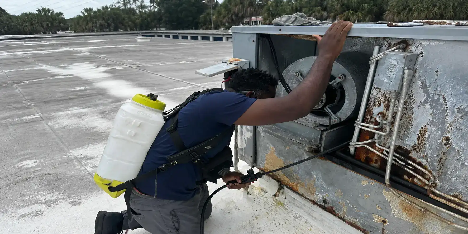 Liberty Air and Electric tech performing rooftop AC coil cleaning at a South Florida property.