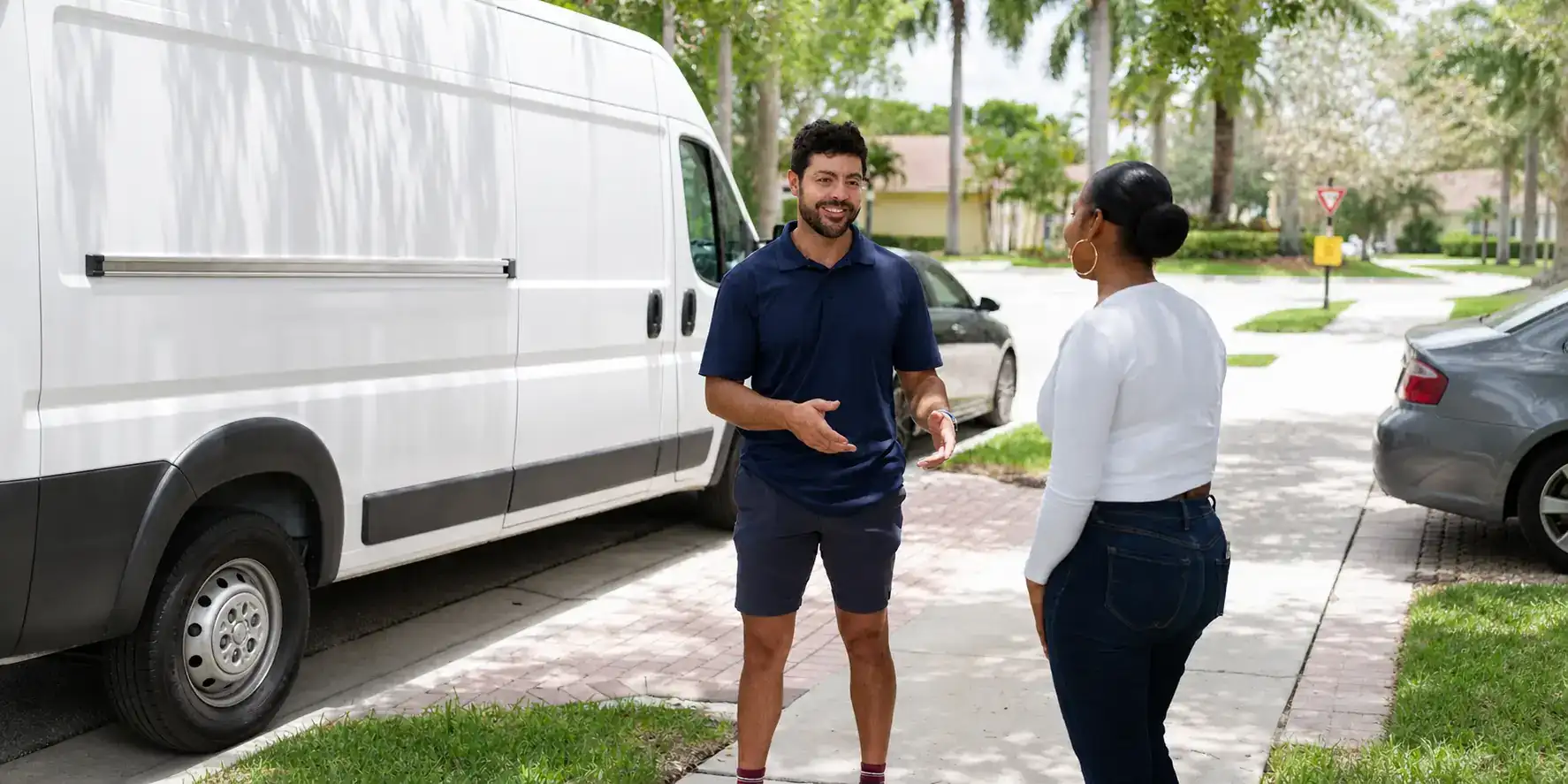 Liberty Air and Electric tech talking with a Wedgefield homeowner in their driveway next to the service van.