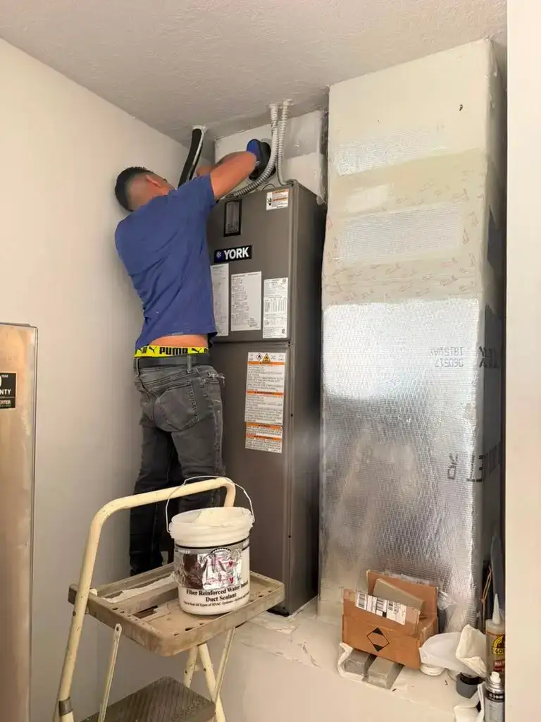 Liberty Air and Electric technician making up the supply connection on a new York air handler installed in a Florida utility closet.