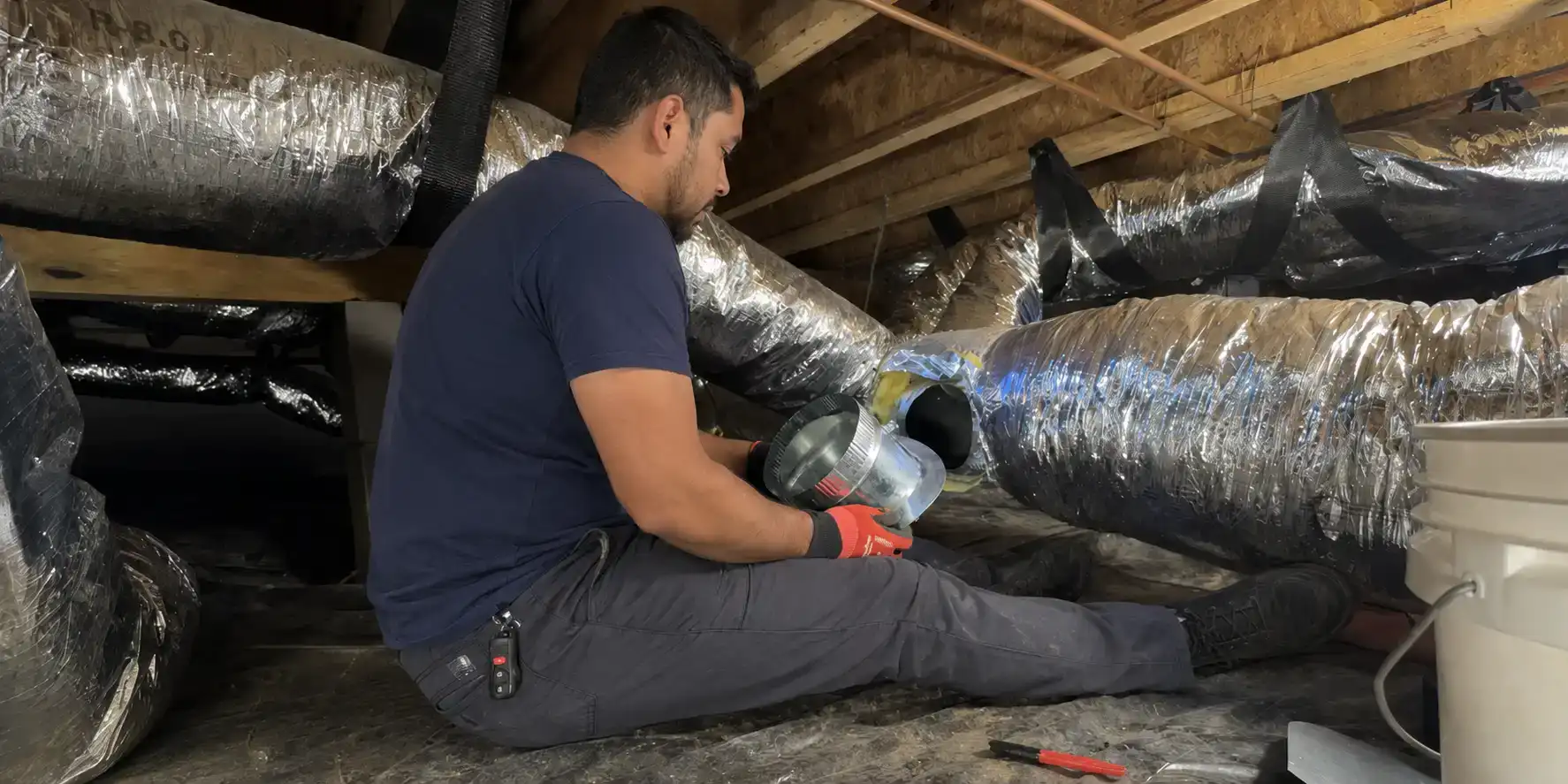Liberty Air and Electric technician installing flex duct in a Florida attic.